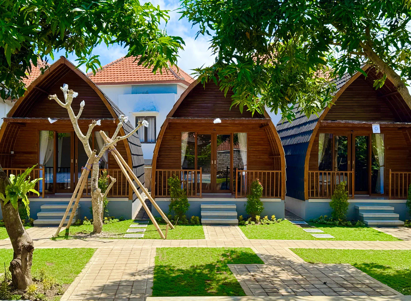 All three handcrafted wooden Lumbung bungalows and manicured garden at Ungasan Center Hostel