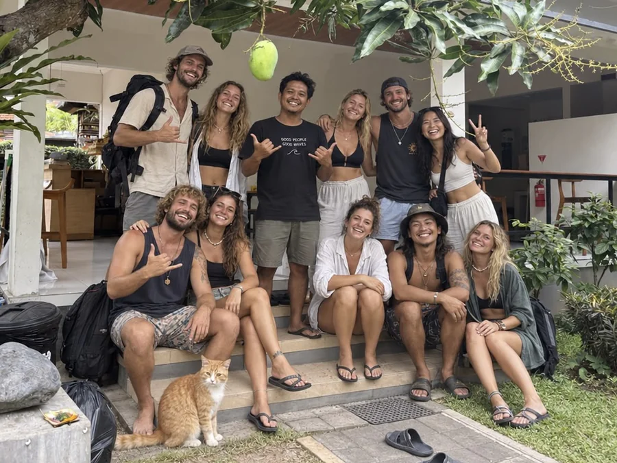 Host Wayan with travelers and Ninja the cat under the mango tree at Ungasan Center Hostel